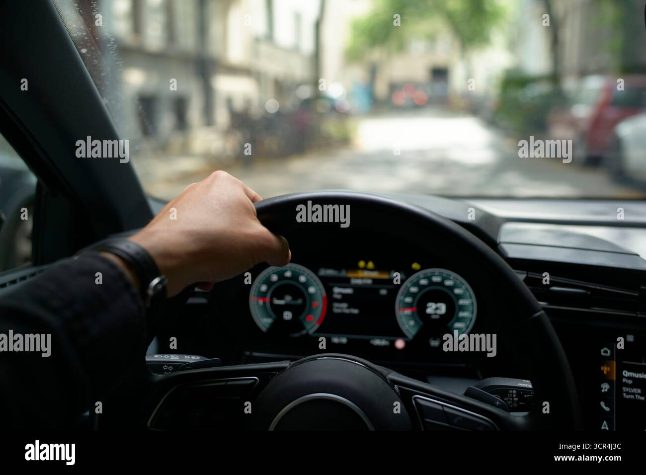 Main sur le volant, conduisant dans une rue floue et ensoleillée de la ville. Allemagne Banque D'Images