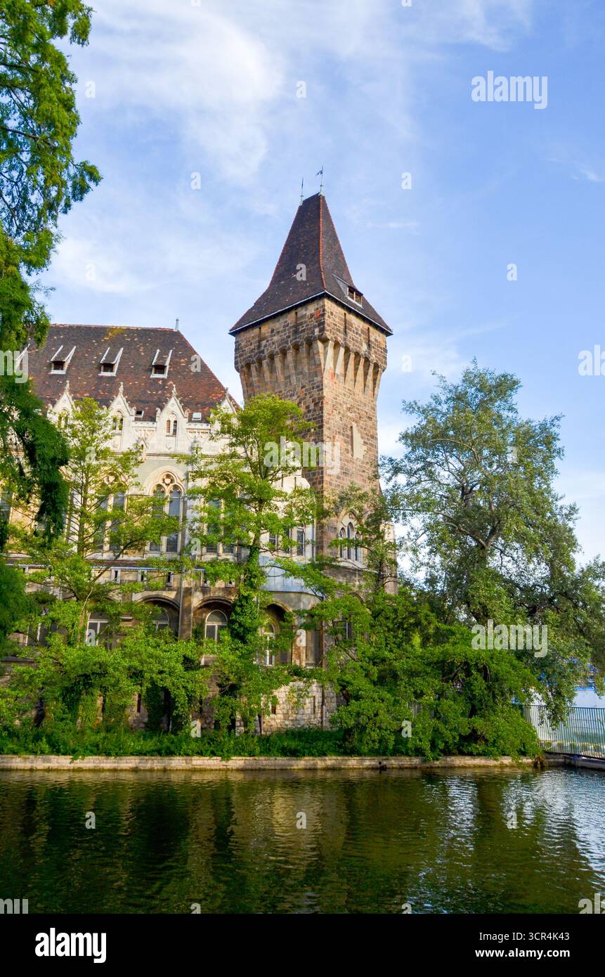 Tour du château de Vajdahunyad avec des murs de pierre et des arbres reflétés dans l'eau à Budapest, Hongrie. Banque D'Images