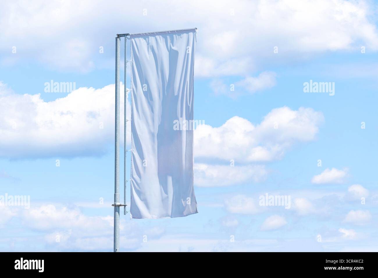 Bannière blanche verticale unique sur le poteau flottant dans le vent avec fond bleu nuageux de ciel, espace publicitaire extérieur Banque D'Images