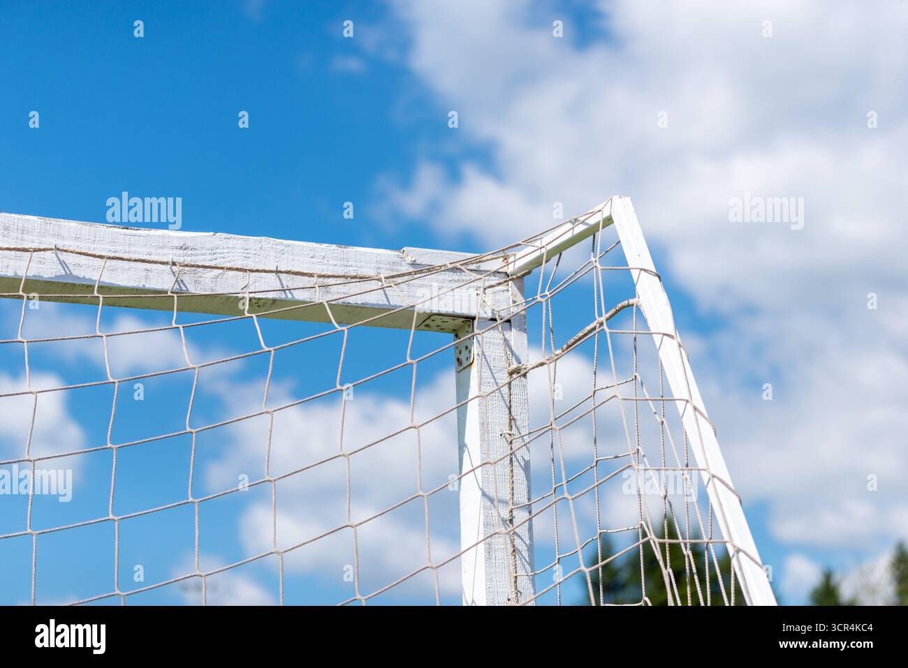 Gros plan du coin du poteau de but de football usé avec filet contre le ciel bleu et les nuages blancs. Banque D'Images