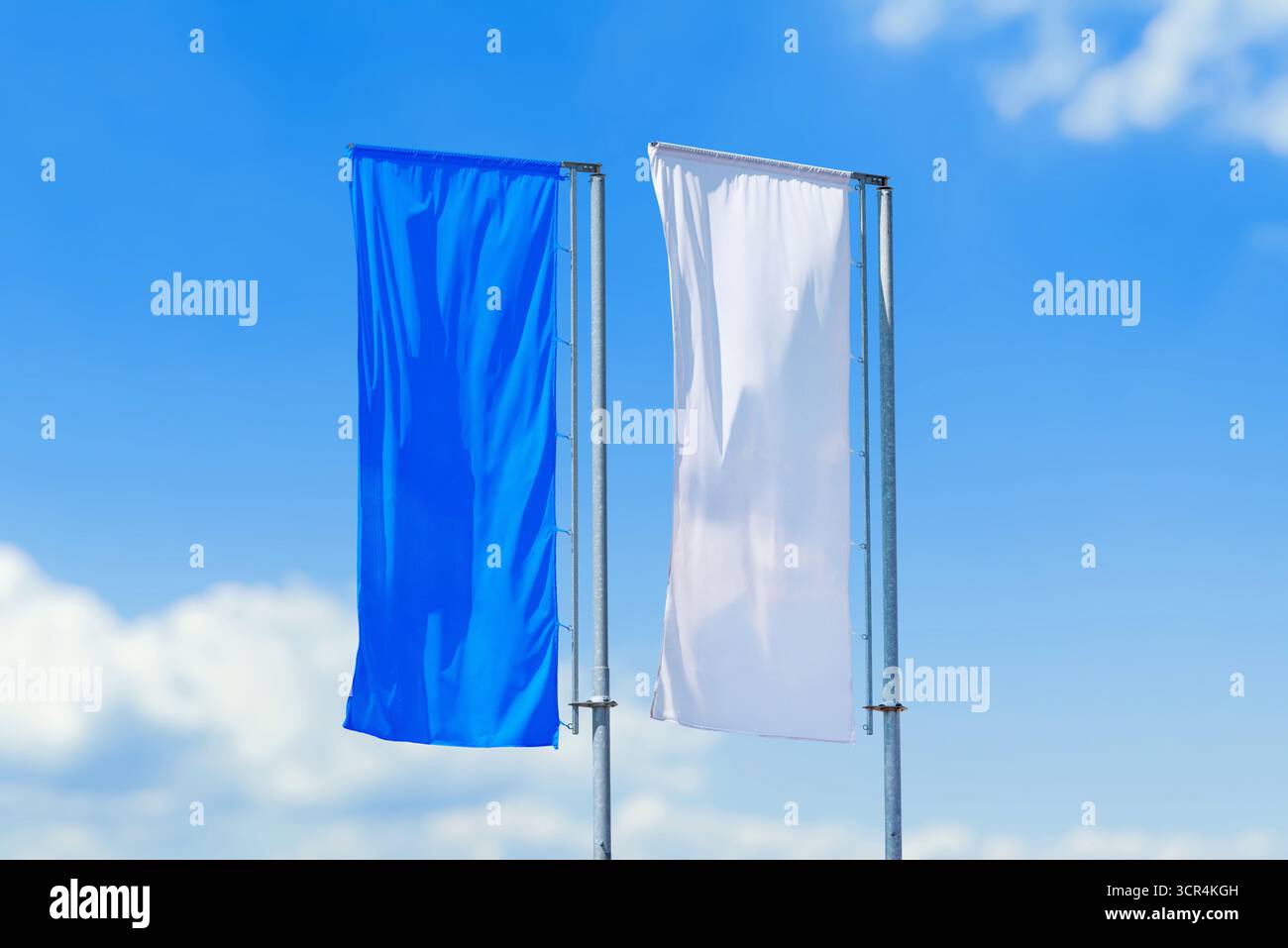Paire de drapeaux verticaux de couleurs bleues et blanches ondulant sur des poteaux contre le ciel clair, la publicité extérieure ou la décoration d'événement. Banque D'Images