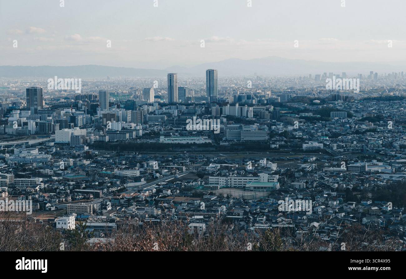 Vue hivernale d'Osaka depuis Minoh, avec des gratte-ciels modernes s'élevant au-dessus de l'étalement urbain dense sous un ciel bleu pâle Banque D'Images