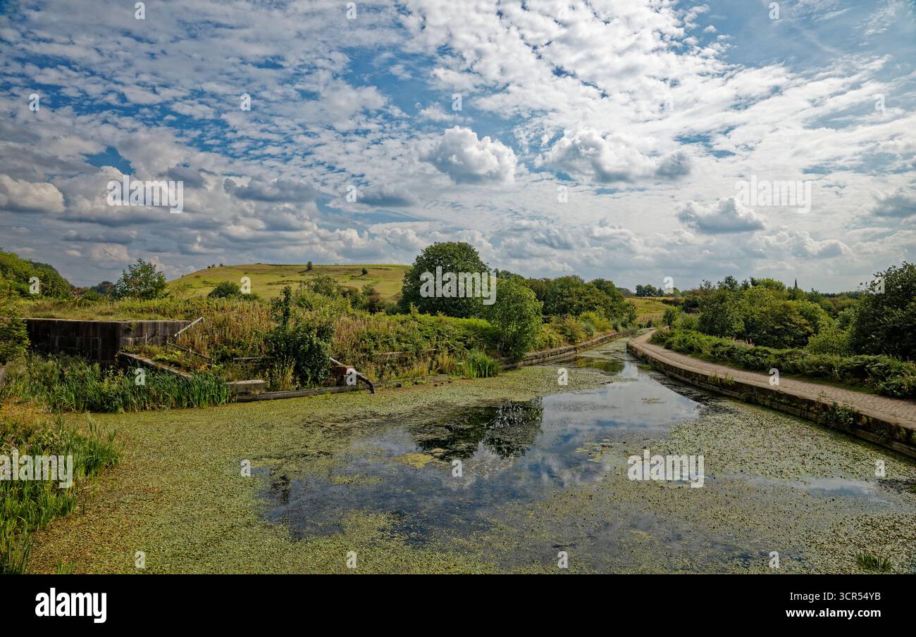 Bassin du canal désaffecté au bas de l'escalier de l'écluse abandonnée avec le canal menant à l'aqueduc Prestolee, Bolton, Greater Manchester. Banque D'Images