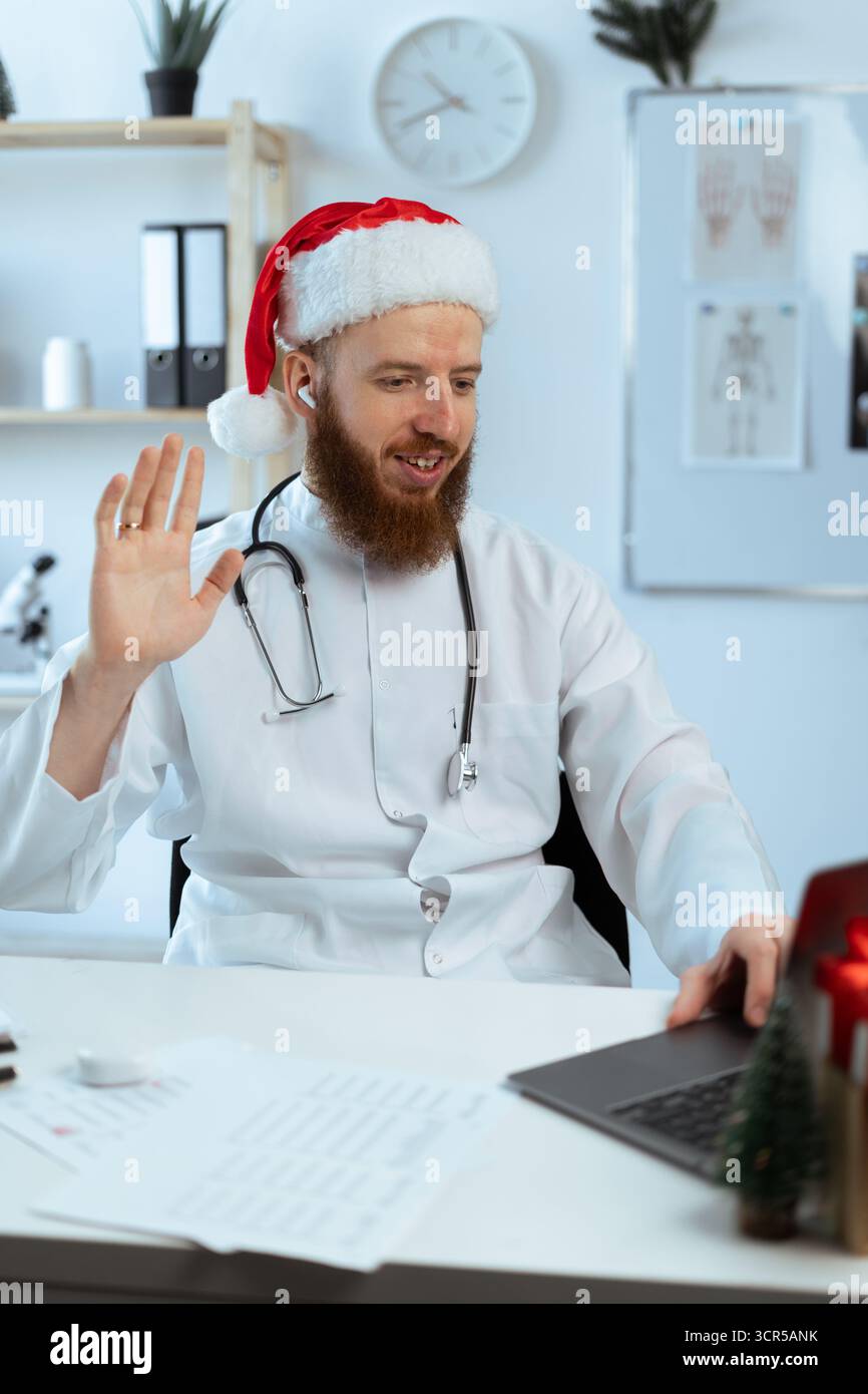 Télémédecine et concept de vacances de noël. Docteur sur le quart de travail sur l'ordinateur portable agitant la main faisant la consultation en ligne à l'hôpital sur chris Banque D'Images