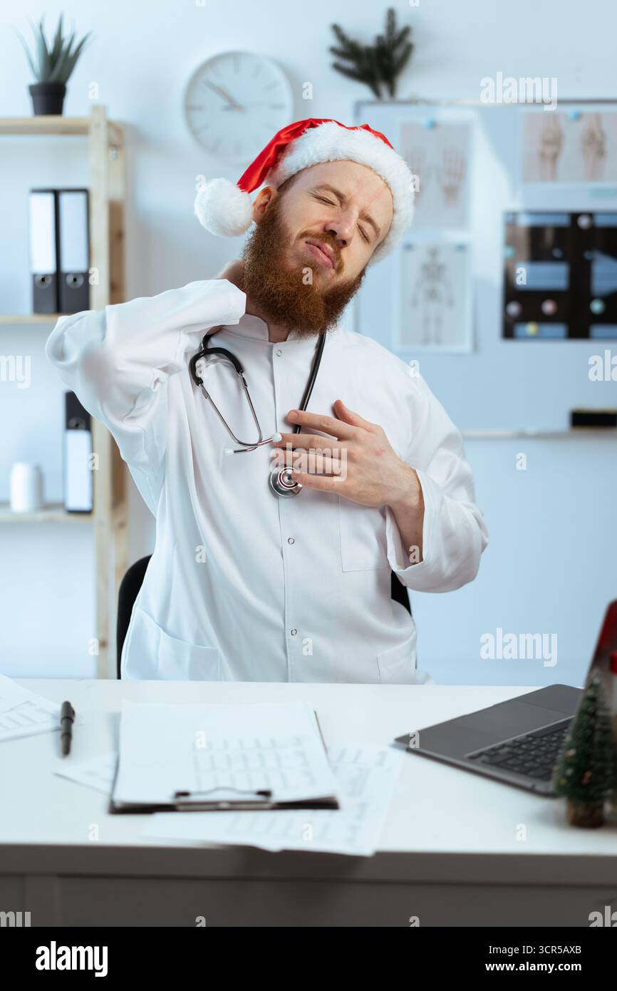 Médecin en poste souffrant de mal de cou surmené à l'hôpital la veille de noël. copier l'espace Banque D'Images