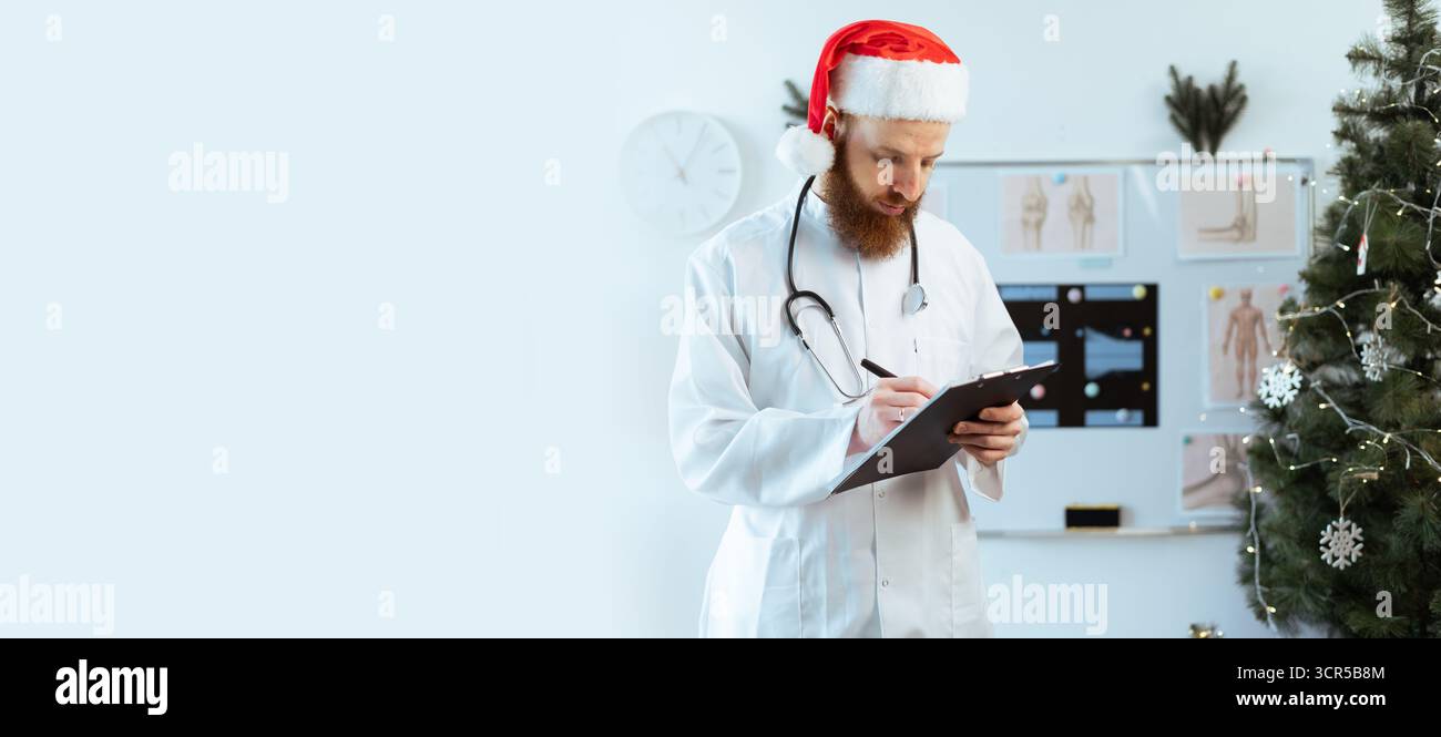 Médecin écrivant des notes sur le presse-papiers pendant le quart de travail de la veille de noël. bannière. Copier l'espace Banque D'Images
