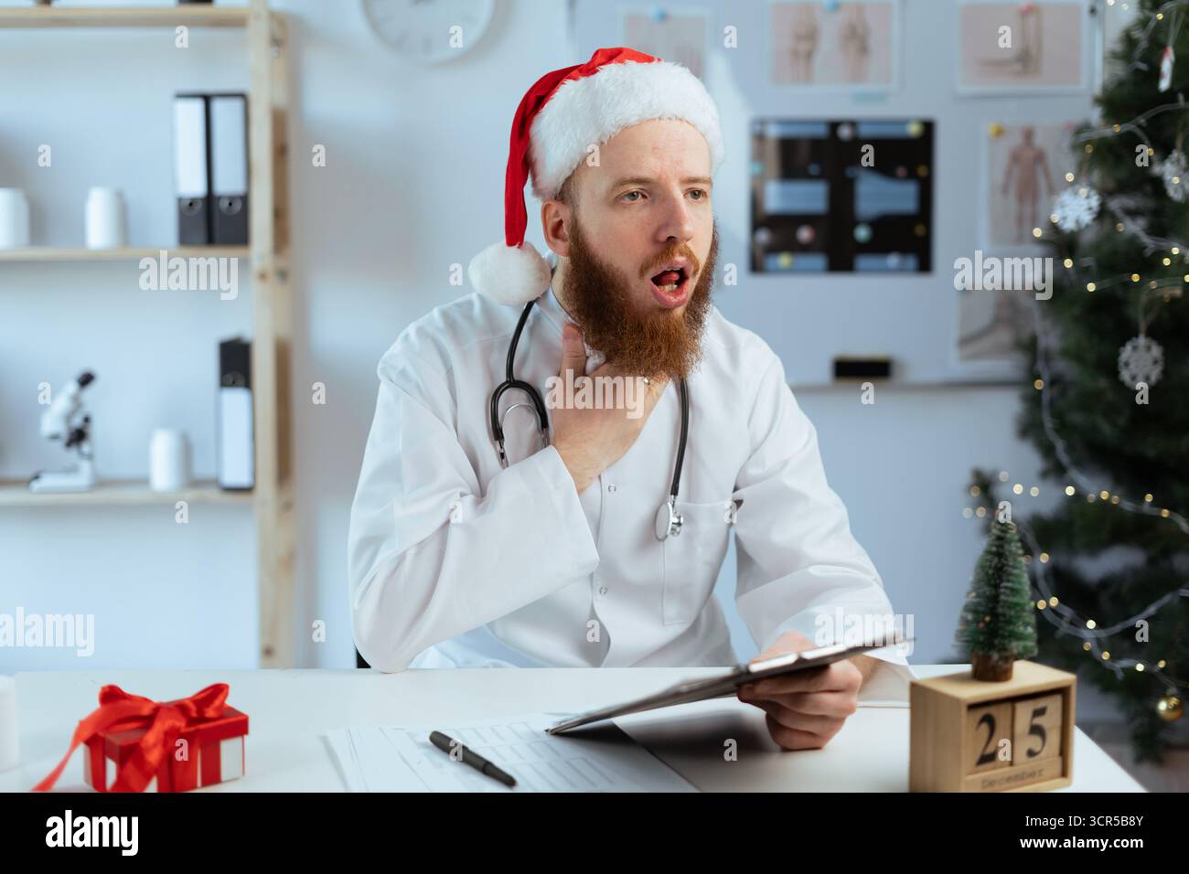 Médecin barbu sur le quart souffrant de problème d'amygdalite et a mal à la gorge tout en travaillant la veille de Noël. copier l'espace Banque D'Images
