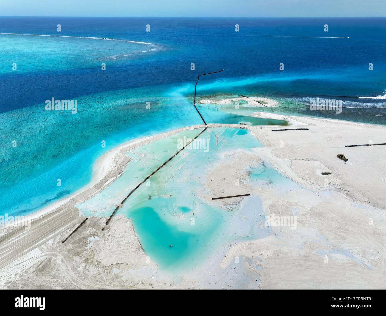 Vue aérienne du contraste frappant entre l'océan sombre et les terres nouvellement récupérées, avec des barrières sombres définissant les bords, Gulhi, Atoll de Malé Sud, Maldives. Banque D'Images