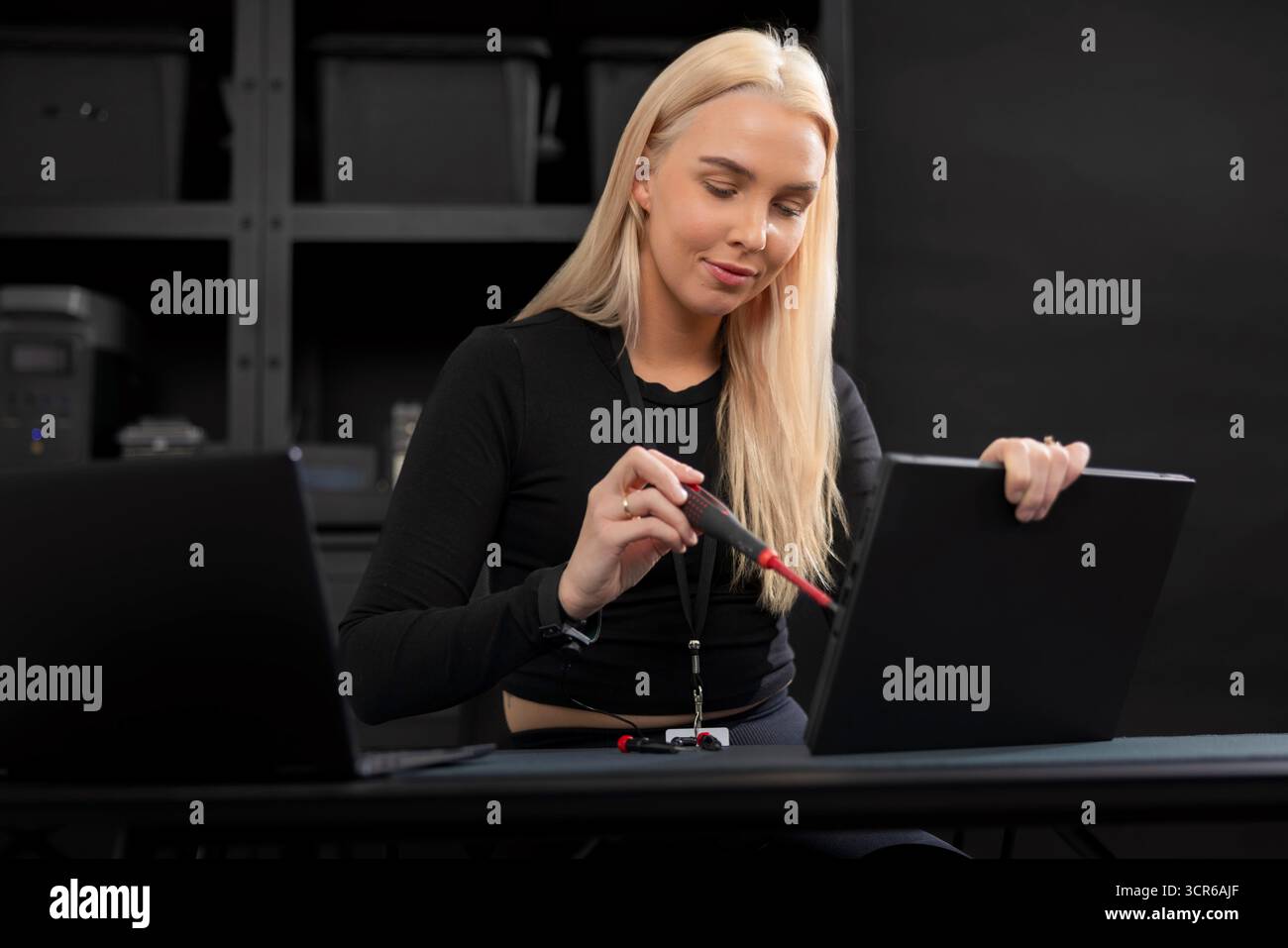 Jeune technicien INFORMATIQUE blonde réparant un ordinateur portable dans une salle de serveurs pendant la maintenance et le diagnostic Banque D'Images