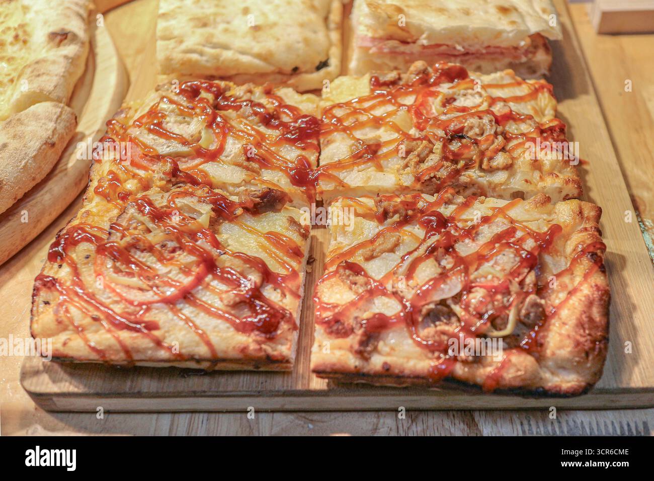 Pizza au jambon carré avec fromage, sauce tomate et mayonnaise, croûte croustillante, servie sur planche de bois. Snack thaïlandais de rue prêt à manger. Banque D'Images
