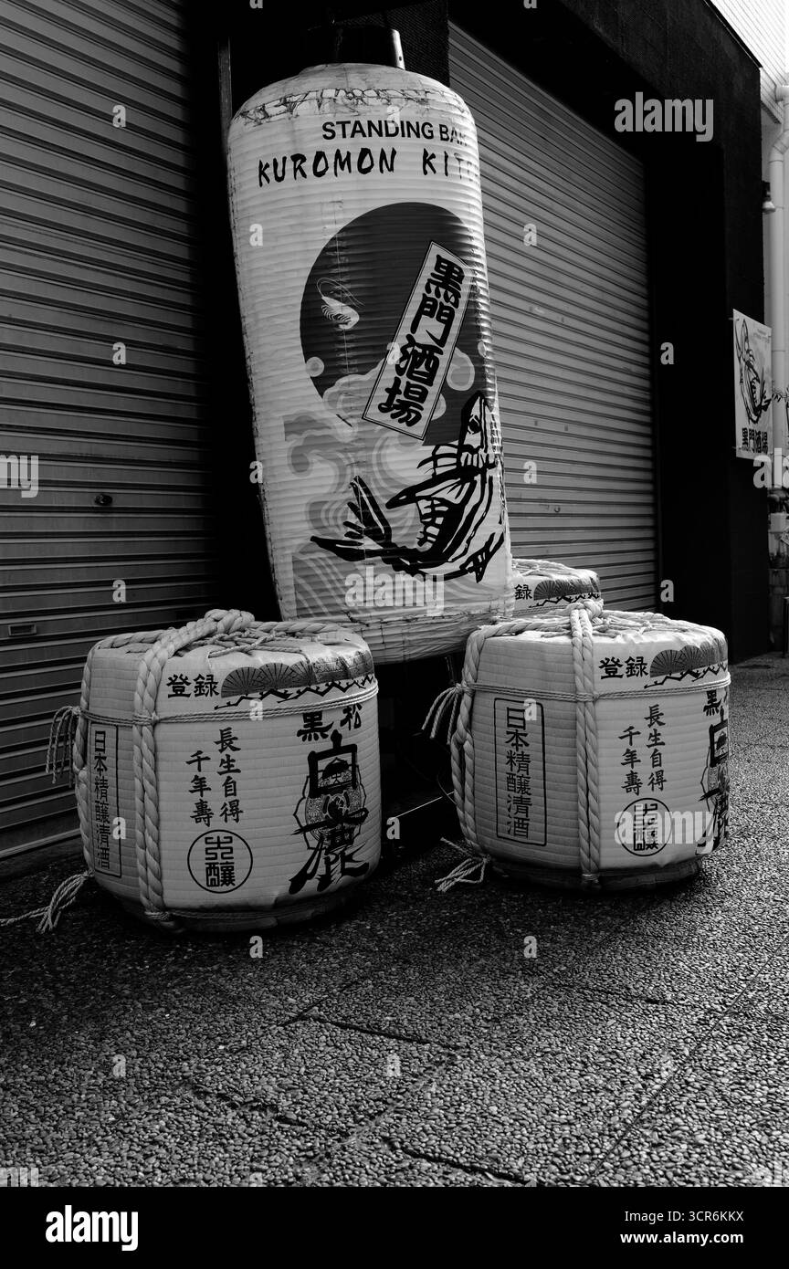 Cliché monochrome de fûts de saké traditionnels et de lanterne à l'extérieur du bar Kuromon Kitchen debout Banque D'Images