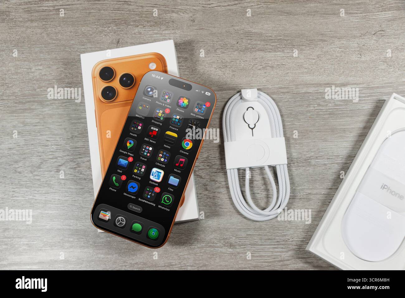 Apple iPhone 17 Pro avec applications affichées, boîte, chargeur et outil de carte SIM sur surface en bois, déballage Banque D'Images