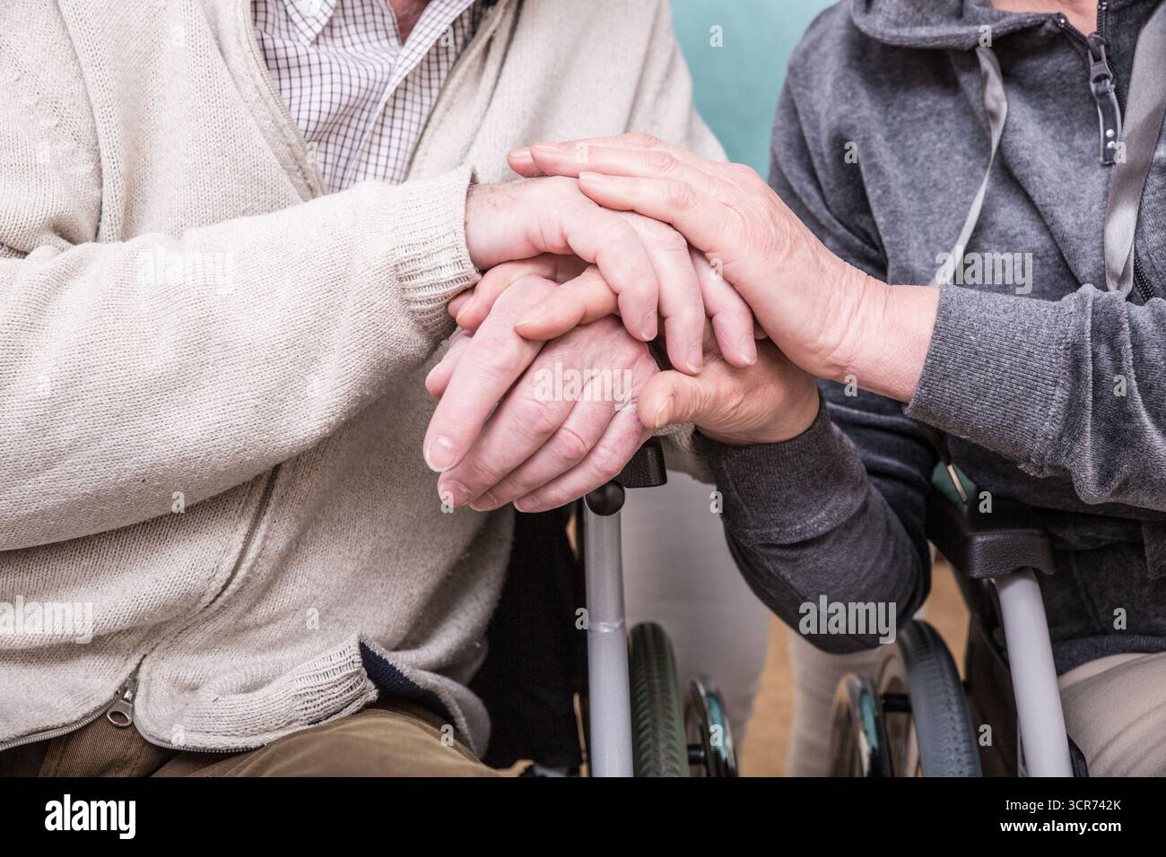 vieux couple tenant les mains en fauteuil roulant Banque D'Images
