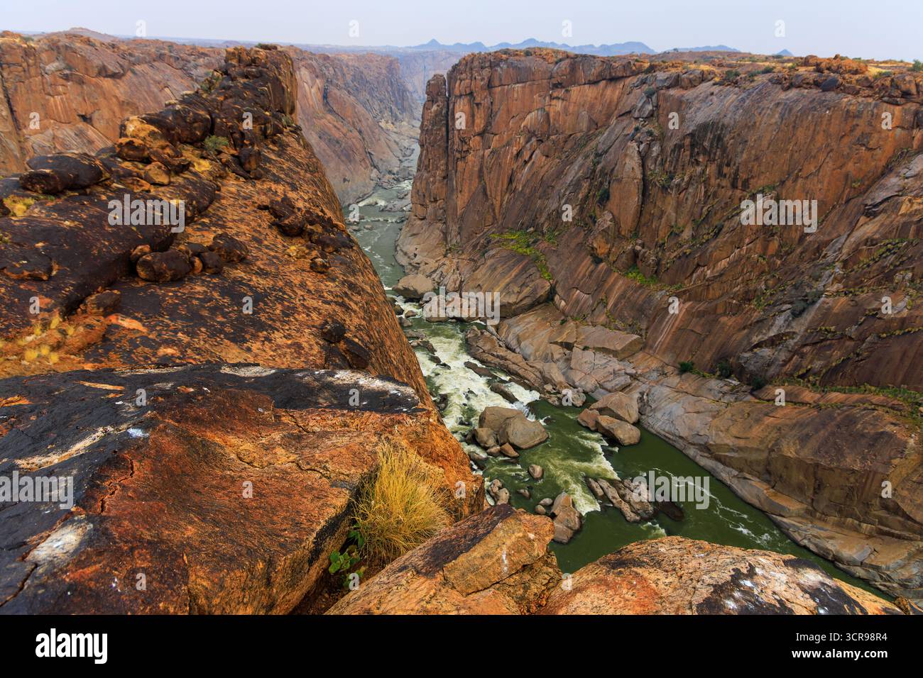 Vue sur la ruée rivière oranger sculptant son chemin à travers le canyon rocheux accidenté, les teintes chaudes contrastant avec l'eau fraîche, Augrabies, Cap Nord, Afrique du Sud. Banque D'Images