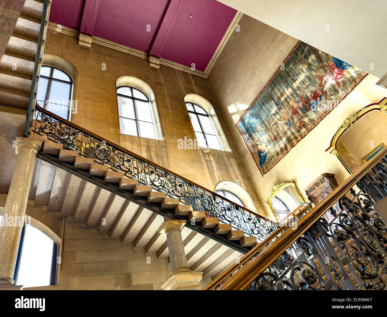 Observez un escalier orné d'une balustrade en fer forgé menant au palier dans le château historique de Bowes avec de grandes fenêtres et une tapisserie spectaculaire du château Barnard Banque D'Images
