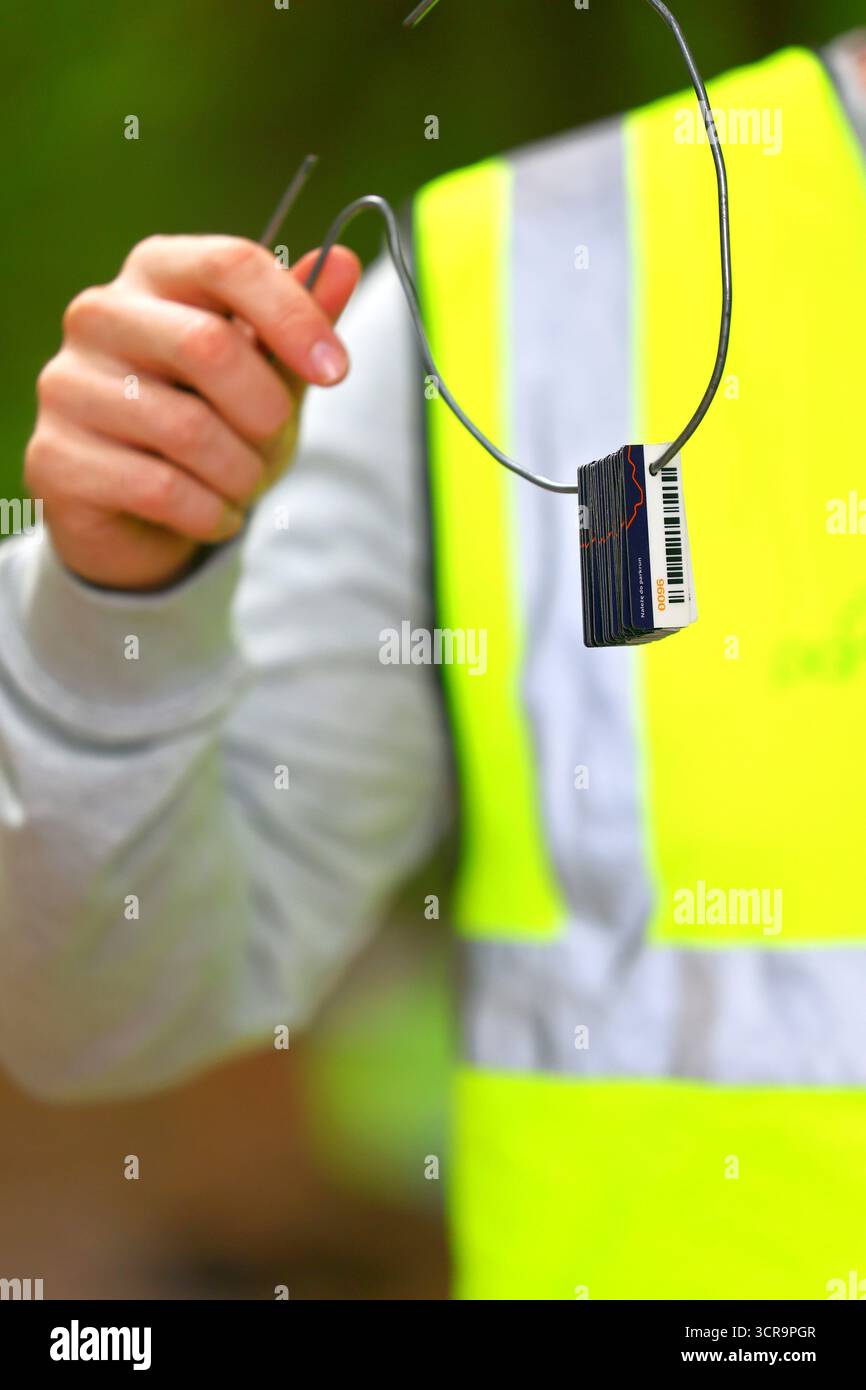 Gros plan d'une personne portant un gilet réfléchissant tenant un anneau en métal avec des jetons parkrun Banque D'Images