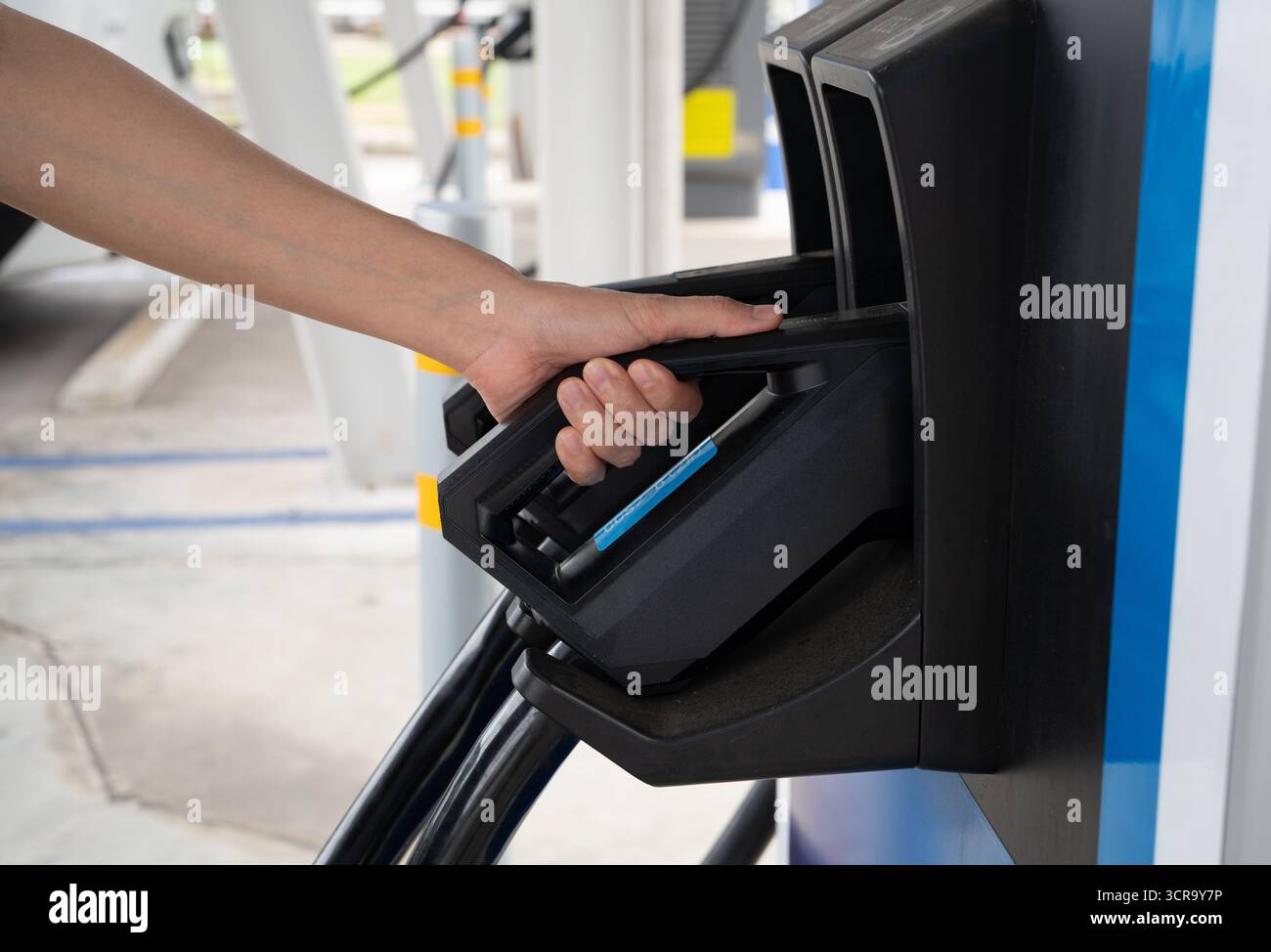 Prise électrique à la main au niveau de la station de charge publique des véhicules électriques pour une alimentation durable de la batterie du véhicule. Infrastructure technologique verte moderne Banque D'Images