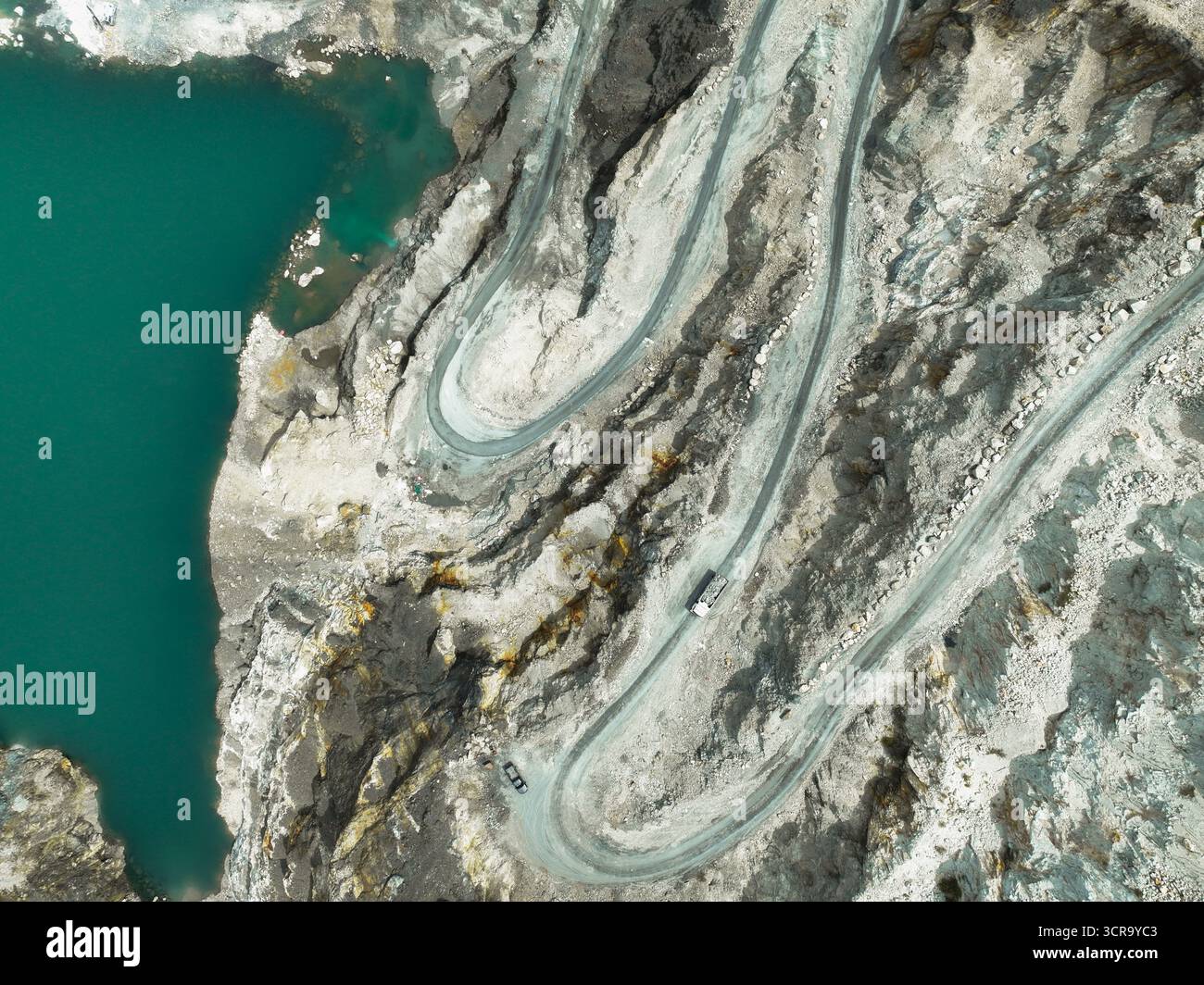 Vue aérienne d'un camion de transport transportant du calcaire brut à travers une carrière à ciel ouvert, montrant les opérations minières industrielles et l'impact environnemental Banque D'Images