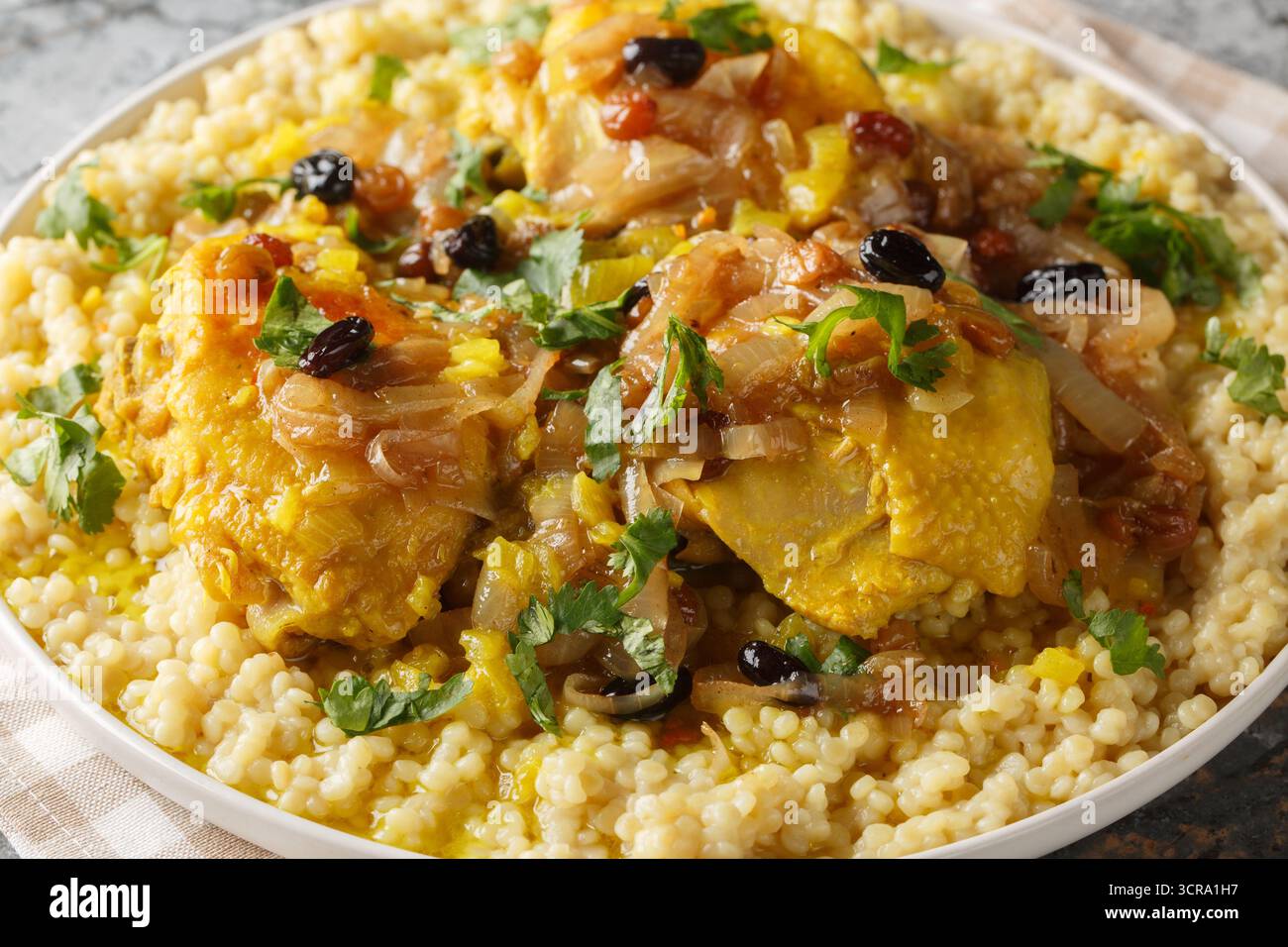 Salé doux couscous de poulet parfumé tfaya est un gros plan de repas réconfortant et spécial sur l'assiette sur la table. Horizontal Banque D'Images