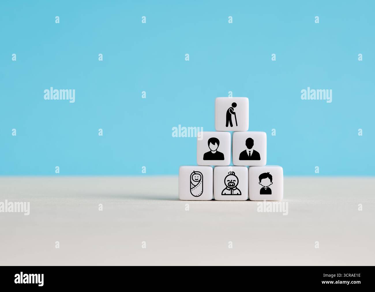 Blocs blancs empilés dans une forme pyramidale représentant le cycle de vie humain avec des icônes de bébé aux personnes âgées sur fond bleu Banque D'Images