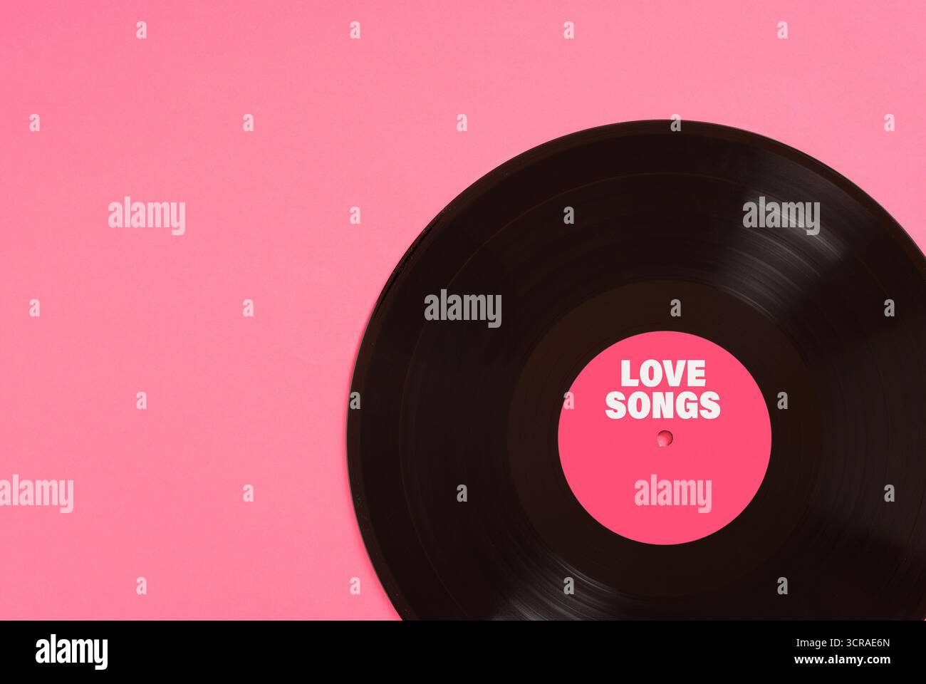 Disque vinyle avec étiquette rose disant chansons d'amour reposant sur un fond rose, parfait pour les projets liés à la musique, la romance, ou la saint-valentin Banque D'Images