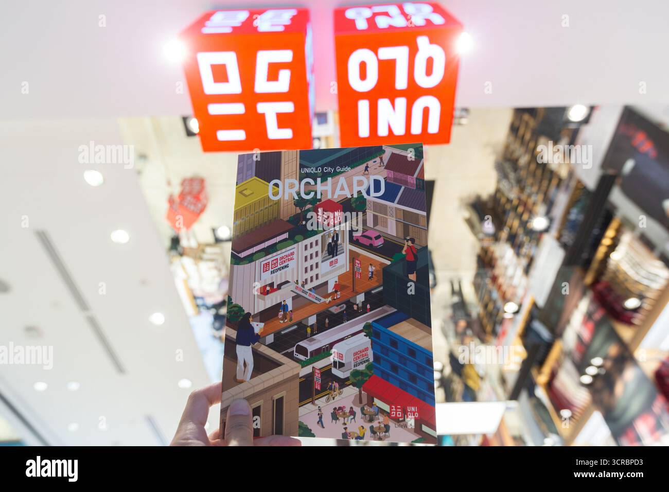 Main tenant le guide de la ville de Orchard Road. Magasin phare Uniqlo à Orchard Central, Singapour. Une puissance de la mode rapide japonaise dans le monde entier. Banque D'Images