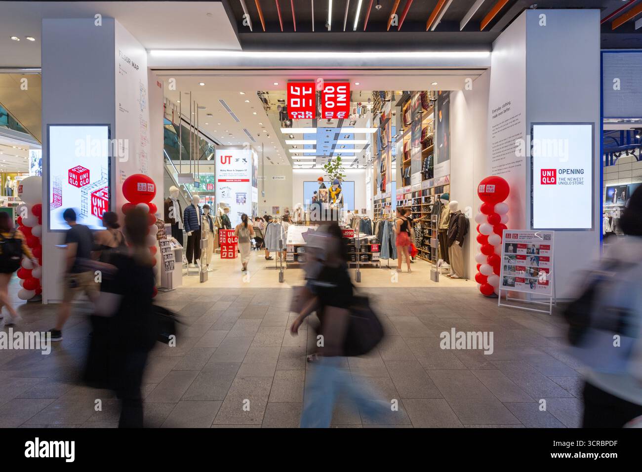 People in Blur motion Walk passe devant le magasin phare Uniqlo à Orchard Central, Singapour. Une position de leader de la mode rapide japonaise dans le monde entier. Banque D'Images