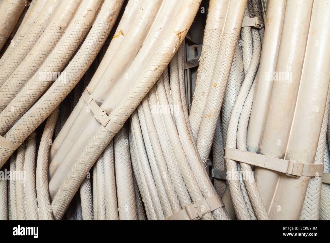 Faisceau de nombreux câbles électriques entrelacés dans une gaine de protection blanche pour l'alimentation, gros plan Banque D'Images