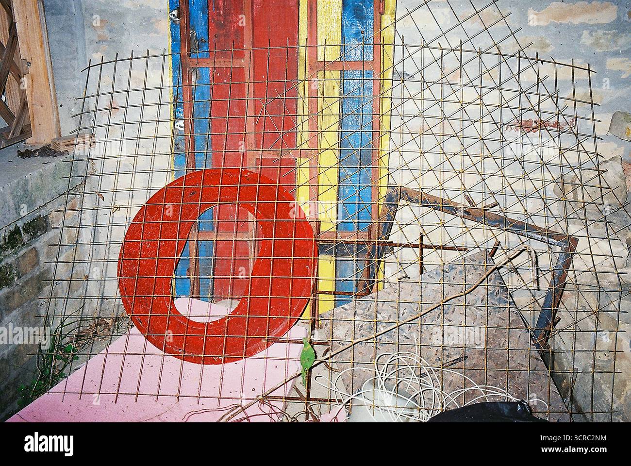 Grande lettre en bois rouge O positionnée derrière un cadre métallique carré, photographiée avec un flash direct dans un style instantané analogique spontané et fort Banque D'Images