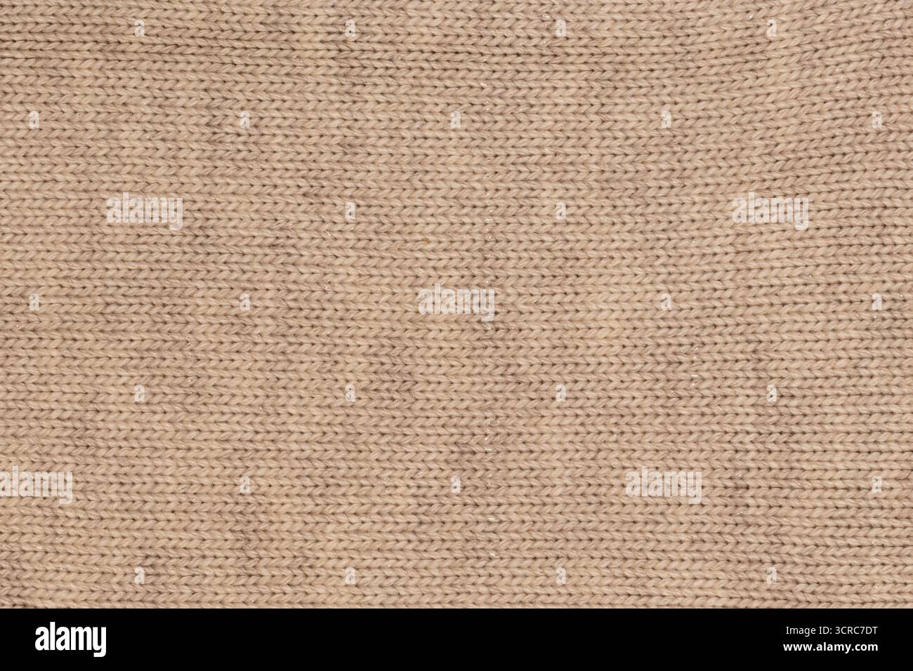Gros plan de tissu de laine tricoté beige avec des accents de fil brillant et des coutures détaillées, créant une texture douce et légèrement étincelante Banque D'Images