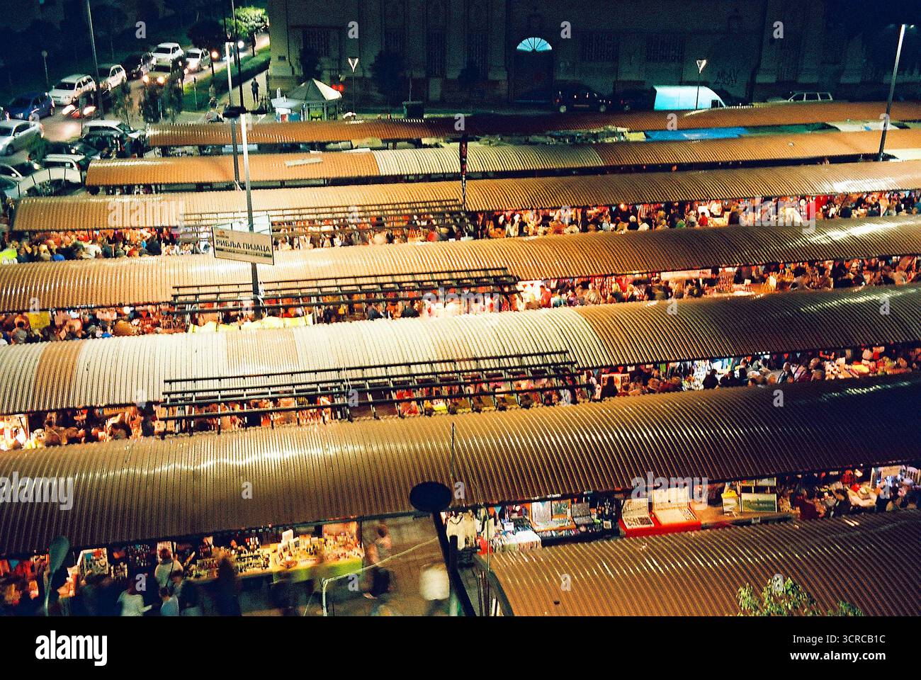 Longues toitures d'un marché aux poissons vues du dessus dans un marché de nuit bondé, rempli de gens et de stands illuminés, capturé sur film analogique. Banque D'Images