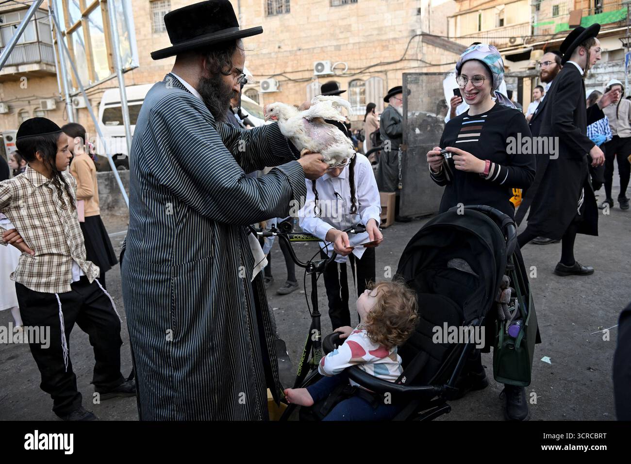 Jérusalem, Israël. 30 septembre 2025. Un juif ultra-orthodoxe tient un poulet au-dessus de la tête d'un bébé tout en exécutant l'ancien rituel juif de Kapparot à Mea Shearim à Jérusalem, le mardi 30 septembre 2025. Le rituel Kapparot est exécuté avant Yom Kippour, le jour des Expiations, tandis que la personne prie en balançant un poulet sur sa tête, ce qui transfère symboliquement les péchés de l'année passée au poulet. Yom Kippour est le jour le plus Saint de l'année juive et commence au coucher du soleil le 1er octobre. Photo de Debbie Hill/ crédit : UPI/Alamy Live News Banque D'Images