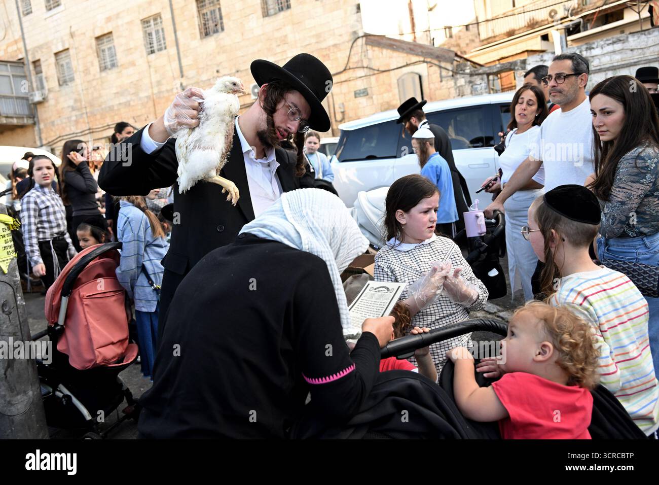 Jérusalem, Israël. 30 septembre 2025. Un homme juif ultra-orthodoxe balançant un poulet sur la tête de sa femme tout en exécutant l'ancien rituel juif de Kapparot à Mea Shearim à Jérusalem, le mardi 30 septembre 2025. Le rituel Kapparot est exécuté avant Yom Kippour, le jour des Expiations, tandis que la personne prie en balançant un poulet sur sa tête, ce qui transfère symboliquement les péchés de l'année passée au poulet. Yom Kippour est le jour le plus Saint de l'année juive et commence au coucher du soleil le 1er octobre. Photo de Debbie Hill/ crédit : UPI/Alamy Live News Banque D'Images
