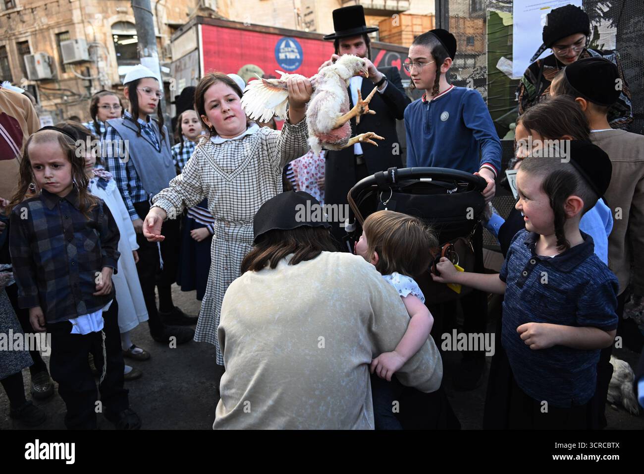 Jérusalem, Israël. 30 septembre 2025. Une jeune fille juive ultra-orthodoxe tient un poulet tout en exécutant l'ancien rituel juif de Kapparot à Mea Shearim à Jérusalem, le mardi 30 septembre 2025. Le rituel Kapparot est exécuté avant Yom Kippour, le jour des Expiations, tandis que la personne prie en balançant un poulet sur sa tête, ce qui transfère symboliquement les péchés de l'année passée au poulet. Yom Kippour est le jour le plus Saint de l'année juive et commence au coucher du soleil le 1er octobre. Photo de Debbie Hill/ crédit : UPI/Alamy Live News Banque D'Images