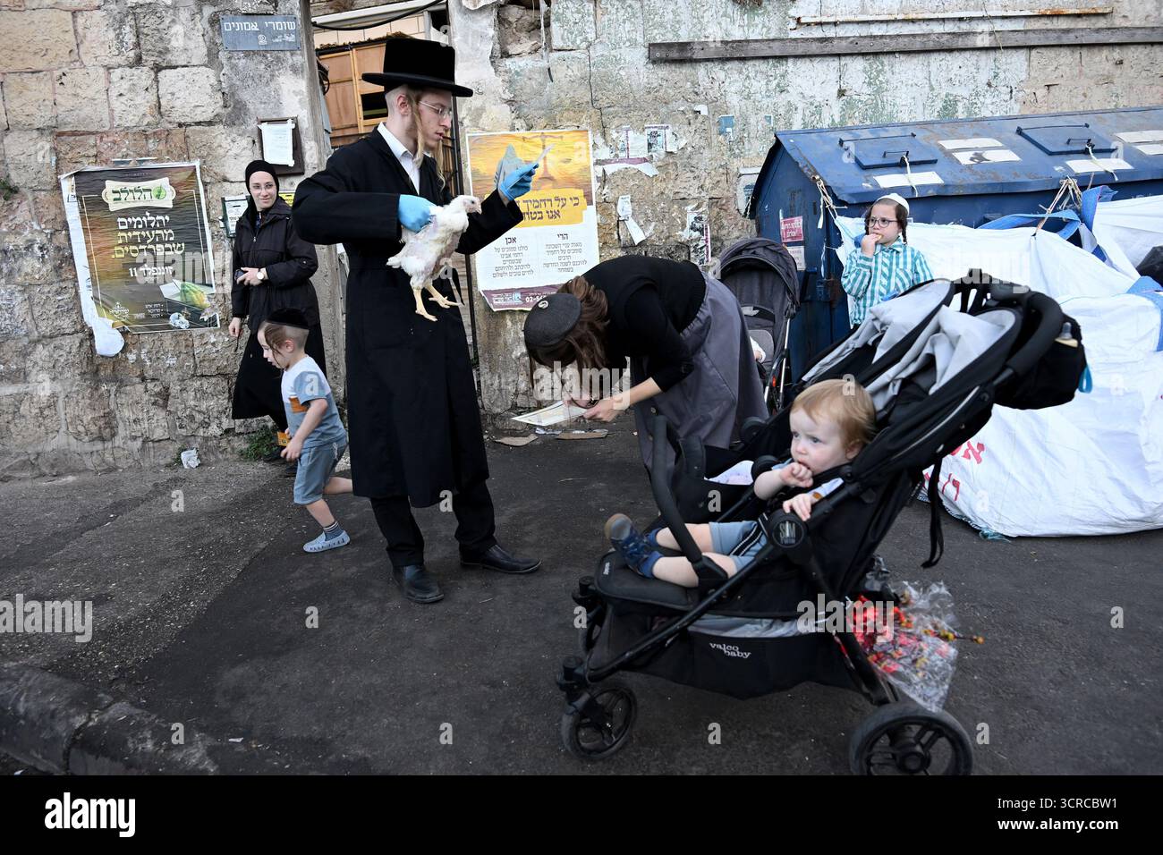 Jérusalem, Israël. 30 septembre 2025. Une femme juive ultra-orthodoxe se penche alors que son mari tient un poulet tout en exécutant l’ancien rituel juif de Kapparot à Mea Shearim à Jérusalem, le mardi 30 septembre 2025. Le rituel Kapparot est exécuté avant Yom Kippour, le jour des Expiations, tandis que la personne prie en balançant un poulet sur sa tête, ce qui transfère symboliquement les péchés de l'année passée au poulet. Yom Kippour est le jour le plus Saint de l'année juive et commence au coucher du soleil le 1er octobre. Photo de Debbie Hill/ crédit : UPI/Alamy Live News Banque D'Images
