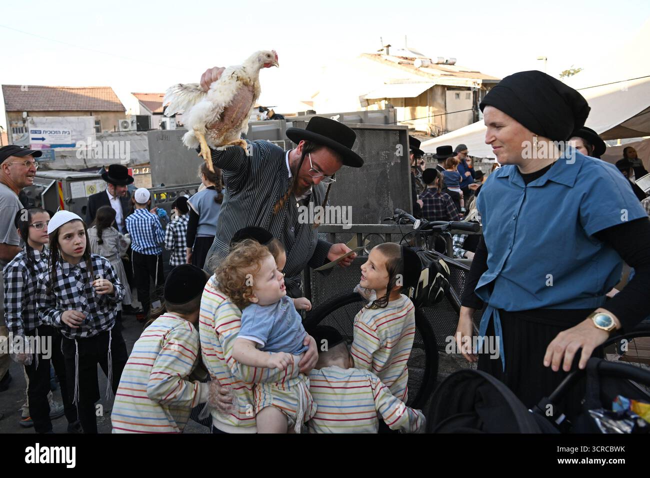 Jérusalem, Israël. 30 septembre 2025. Un homme juif ultra-orthodoxe balançant un poulet au-dessus de la tête de ses enfants tout en exécutant l'ancien rituel juif de Kapparot à Mea Shearim à Jérusalem, le mardi 30 septembre 2025. Le rituel Kapparot est exécuté avant Yom Kippour, le jour des Expiations, tandis que la personne prie en balançant un poulet sur sa tête, ce qui transfère symboliquement les péchés de l'année passée au poulet. Yom Kippour est le jour le plus Saint de l'année juive et commence au coucher du soleil le 1er octobre. Photo de Debbie Hill/ crédit : UPI/Alamy Live News Banque D'Images