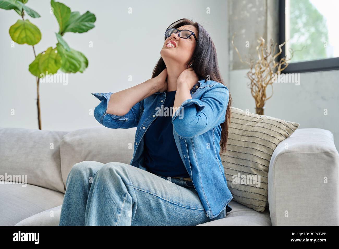 Jeune femme tenant son cou avec ses mains, douleurs musculaires Banque D'Images