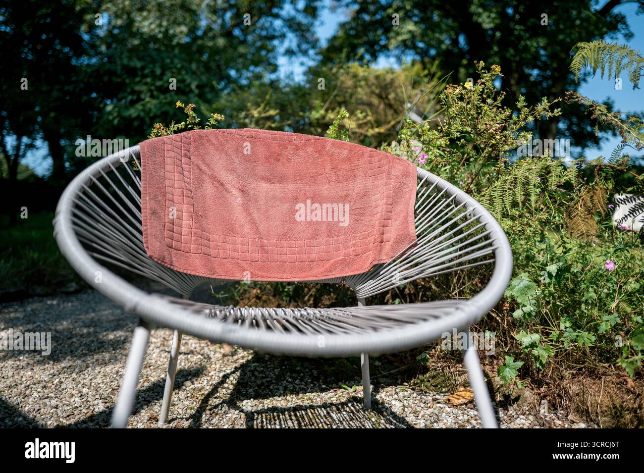 Chaise de jardin ronde blanche en rotin, chaise solaire, utilisé comme cheval de vêtements, serviette rose de séchage, Banque D'Images