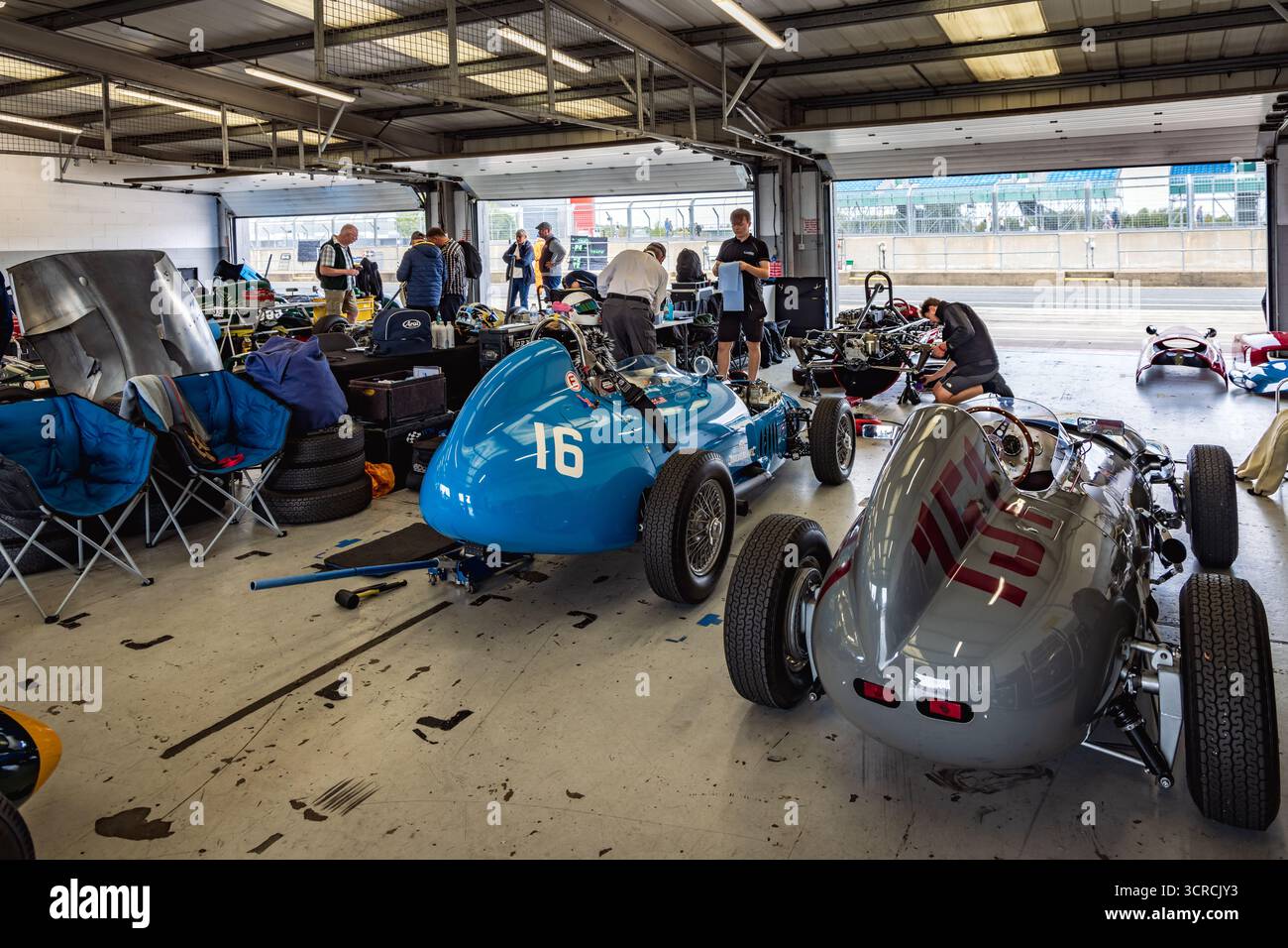 Des voitures de course historiques sont préparées dans l'un des garages de la voie des stands au festival annuel de courses automobiles classiques de Silverstone. Banque D'Images