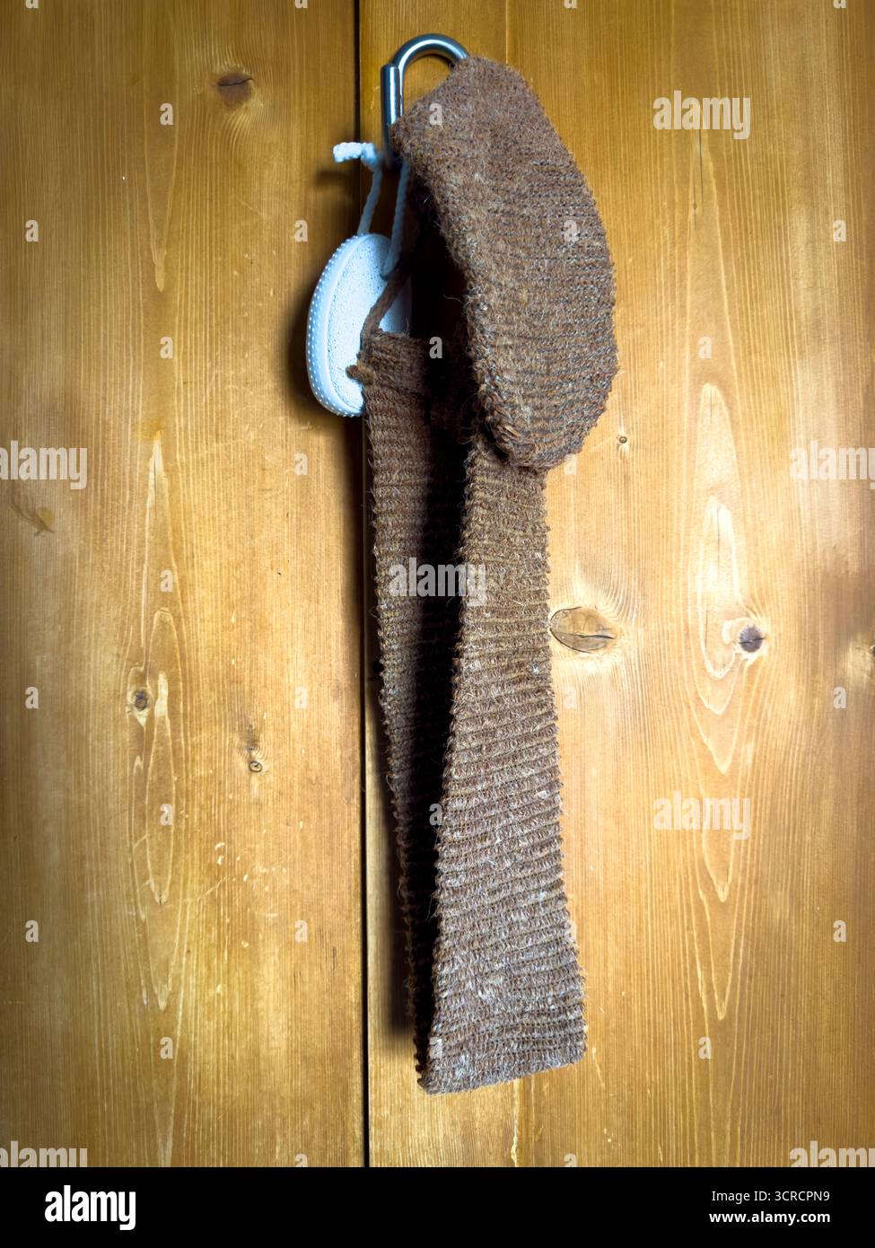 Spa à la maison Natural chanvre Back Scrubber et Pierre ponce accrochée sur la porte en bois pour l'auto-soin et le bien-être - Image de stock capturée avec un smartphone