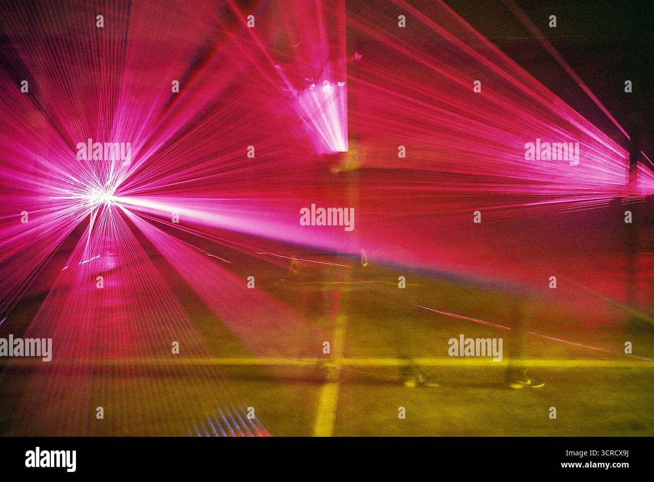 Photo de film analogique de faisceaux lumineux rouges et violets coupant à travers la brume dans un ensemble de garage. Les lasers s'étendent vers la caméra - surréaliste, graveleux, atmosphérique. Banque D'Images