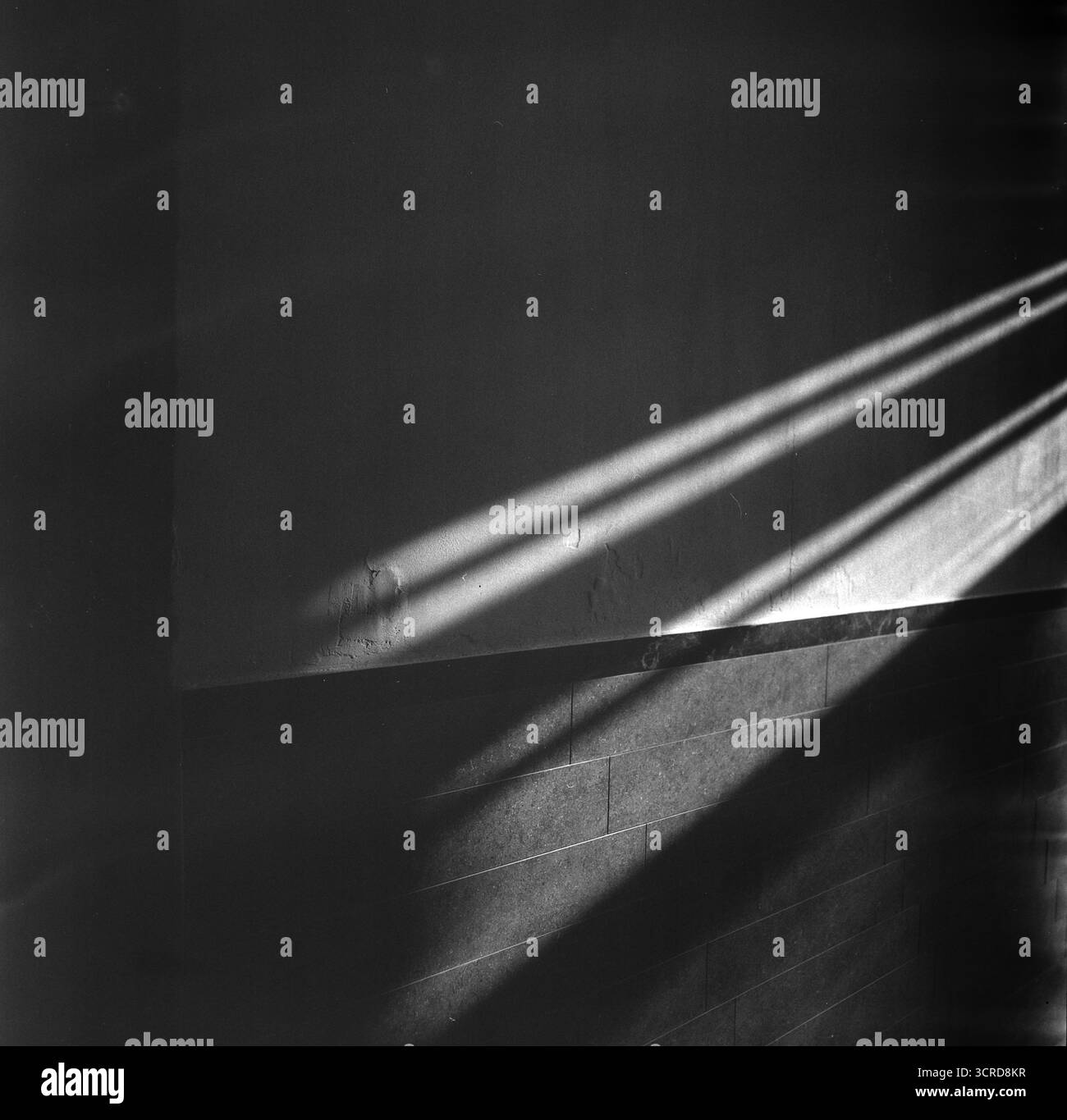 Format moyen noir et blanc. De longs rayons de soleil d'hiver s'étendent sur le mur d'entrée d'un bâtiment vieux de 90 ans. Géométrie silencieuse du temps et de la lumière. Banque D'Images