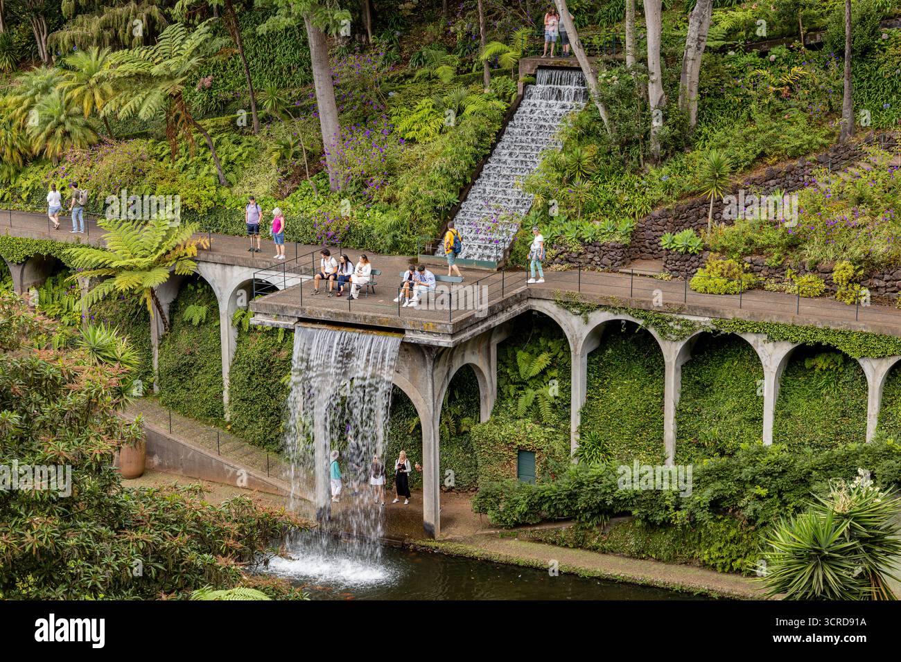 Les touristes apprécient les magnifiques jardins en couches et la cascade avec une végétation luxuriante et des sentiers voûtés dans un cadre paisible de parc Monte Palace Gardens Madère Banque D'Images