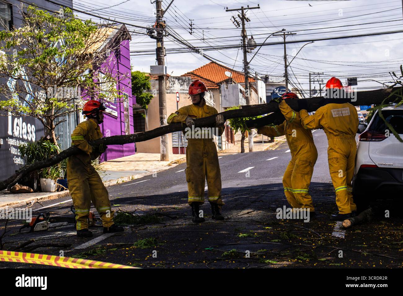 Marilia, SP, Brésil, 22 septembre 2025. Des pompiers en tenue de protection jaune dégagent un arbre tombé d'une rue dans le centre-ville de Marilia Banque D'Images