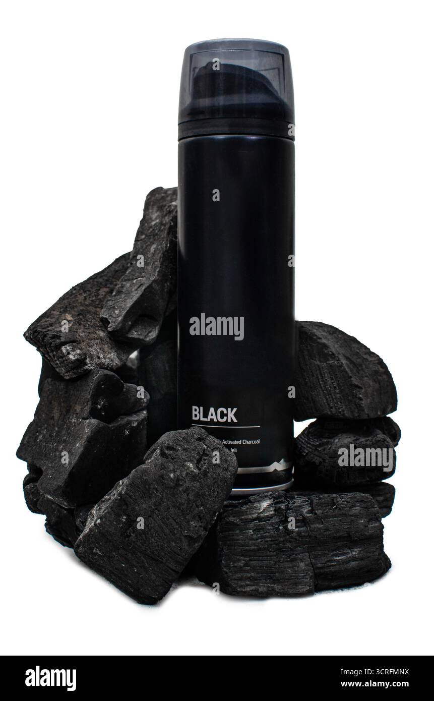 Photographie d'un récipient lisse, noir, cylindrique pour un produit cosmétique, éventuellement de la mousse à raser ou du déodorant, entouré de morceaux non traités Banque D'Images