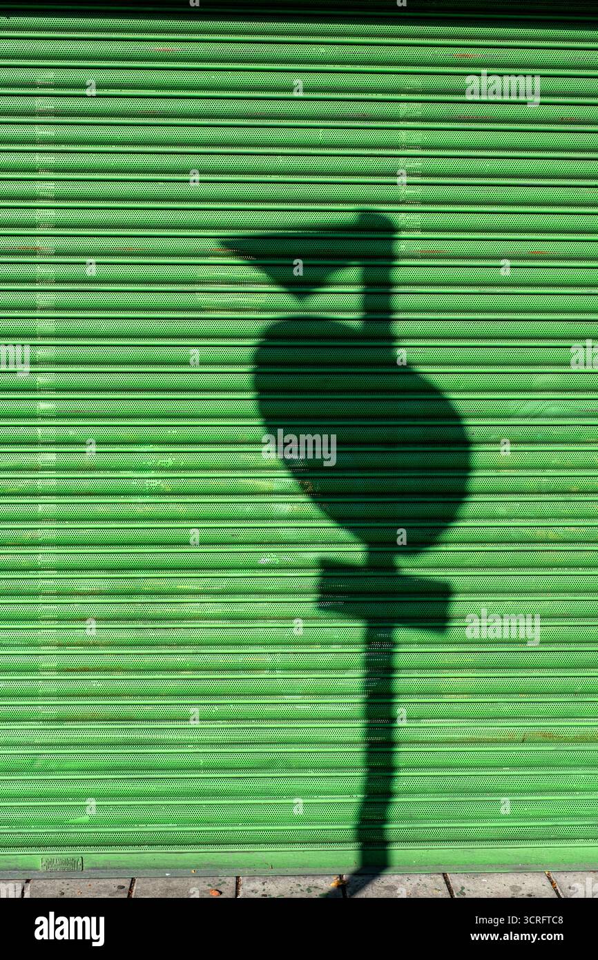 Ombre du panneau de signalisation sur l'obturateur vert fermé de la boutique Banque D'Images