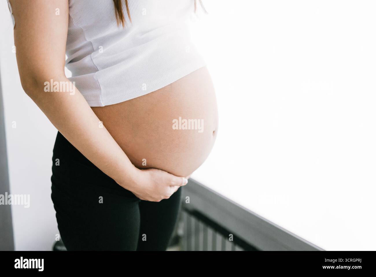 Gros plan du ventre enceinte de la jeune femme caucasienne dans le débardeur blanc Banque D'Images