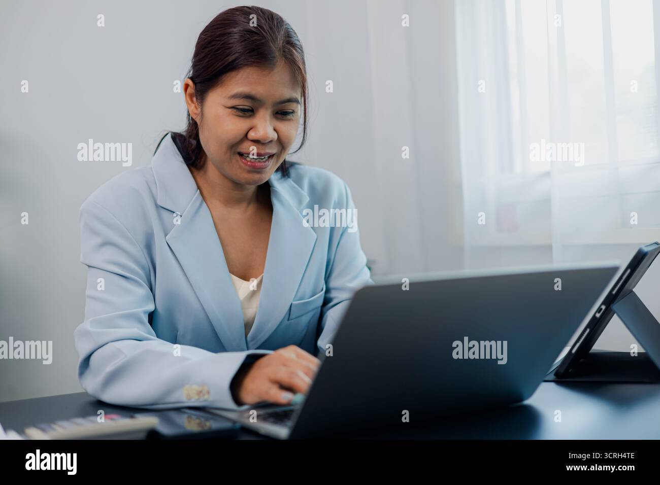 Femme d'affaires asiatique en costume formel agitant la main pendant la réunion d'appel vidéo sur ordinateur portable au bureau. Salutation professionnelle de femme dans la conférence en ligne. Concep Banque D'Images