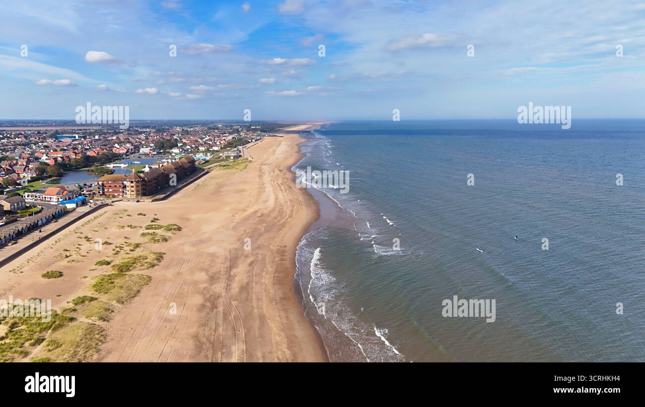 Vue aérienne donnant sur la longue plage dorée sur la côte du Lincolnshire avec les vagues lançant doucement le rivage. Banque D'Images