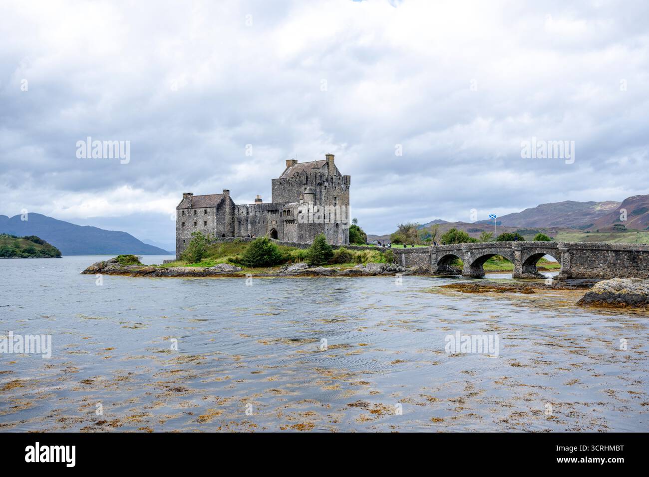Un château médiéval escarpé se trouve sur un îlot rocheux, entouré d'une eau bleue calme et de collines lointaines. Cette forteresse intemporelle évoque l'histoire, scénographe maritime Banque D'Images
